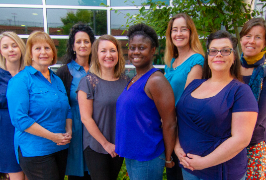 A group of eight people stand together smiling