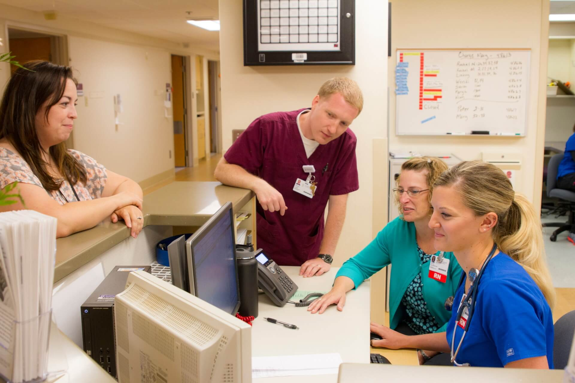 A group of four healthcare professionals gather around a computer at a desk